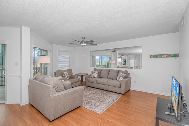 living room with hardwood / wood-style flooring, ceiling fan, and a textured ceiling