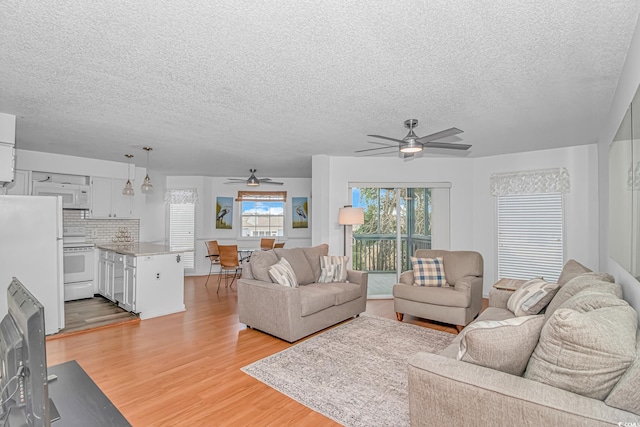 living room featuring a textured ceiling, ceiling fan, and light wood-type flooring