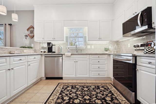 kitchen with light tile patterned floors, sink, appliances with stainless steel finishes, white cabinets, and decorative light fixtures