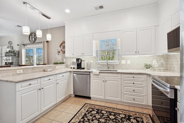 kitchen with appliances with stainless steel finishes, pendant lighting, white cabinets, and decorative backsplash