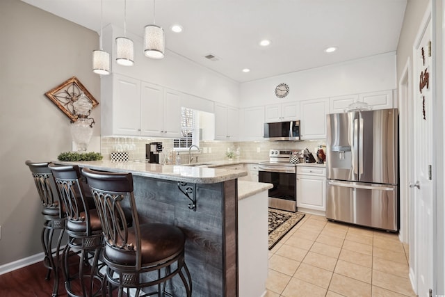 kitchen featuring stainless steel appliances, white cabinetry, a breakfast bar, and kitchen peninsula