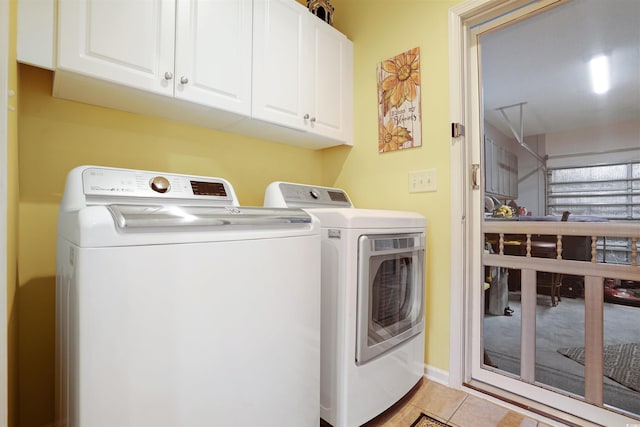 washroom with separate washer and dryer, light tile patterned floors, and cabinets