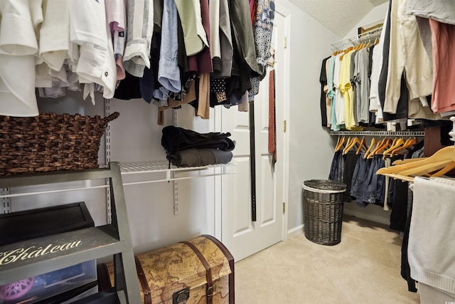 walk in closet with lofted ceiling and light carpet