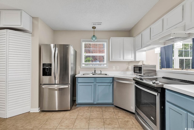 kitchen featuring blue cabinetry, decorative light fixtures, stainless steel appliances, and a healthy amount of sunlight