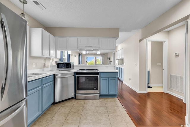 kitchen featuring blue cabinets, decorative light fixtures, light hardwood / wood-style flooring, white cabinetry, and appliances with stainless steel finishes