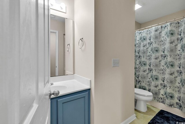 bathroom with a shower with shower curtain, vanity, toilet, and tile patterned floors