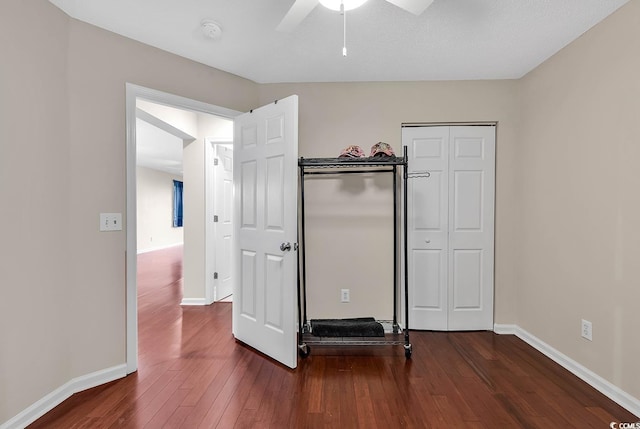unfurnished bedroom with dark wood-style flooring, baseboards, ceiling fan, and a closet