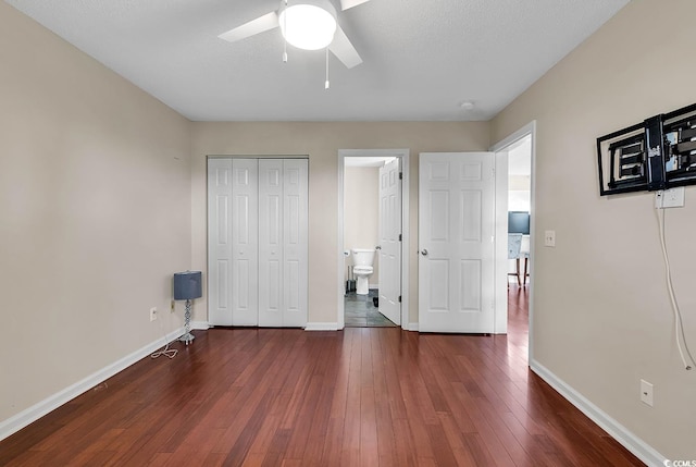 unfurnished bedroom with a closet, a textured ceiling, ceiling fan, ensuite bathroom, and dark hardwood / wood-style floors