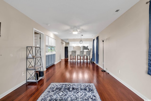 dining space featuring ceiling fan with notable chandelier and dark wood-type flooring