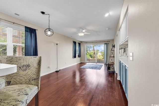 living room featuring baseboards, ceiling fan, visible vents, and dark wood finished floors