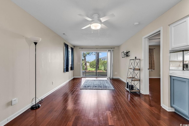 interior space with baseboards, dark wood finished floors, and ceiling fan