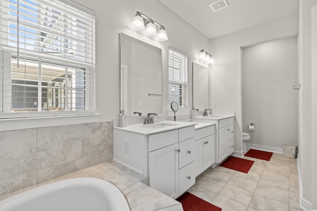 bathroom with plenty of natural light, vanity, tiled tub, and tile patterned floors