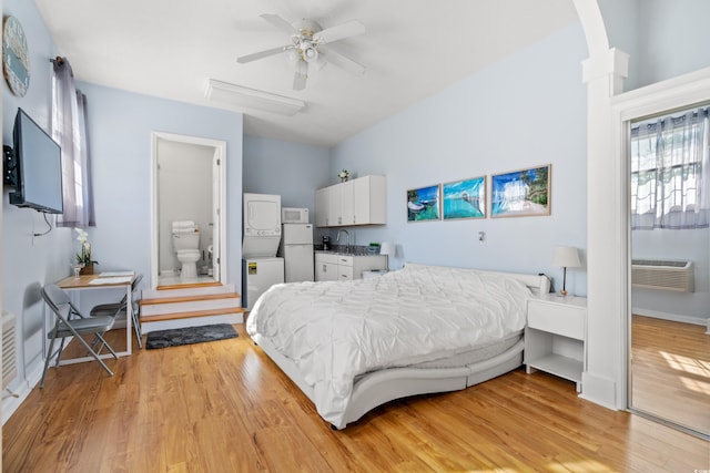 bedroom with ceiling fan, white refrigerator, a wall mounted air conditioner, and light wood-type flooring