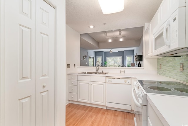 kitchen featuring white cabinets, light hardwood / wood-style flooring, white appliances, sink, and a textured ceiling