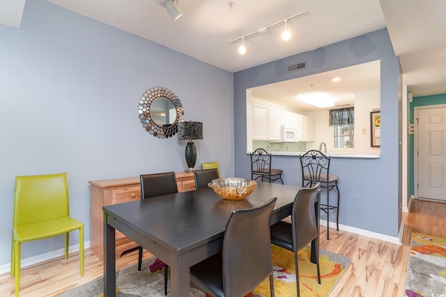 dining area featuring a textured ceiling and light hardwood / wood-style floors