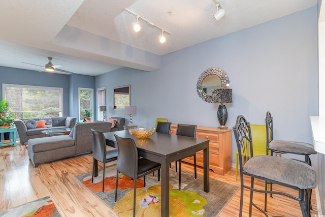 dining space with a textured ceiling, rail lighting, ceiling fan, and hardwood / wood-style flooring