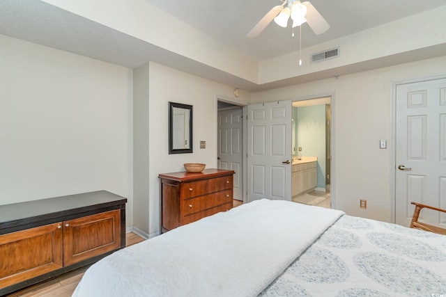 bedroom featuring ceiling fan, ensuite bathroom, and light hardwood / wood-style floors