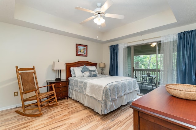 bedroom featuring a raised ceiling, ceiling fan, light hardwood / wood-style flooring, and access to exterior