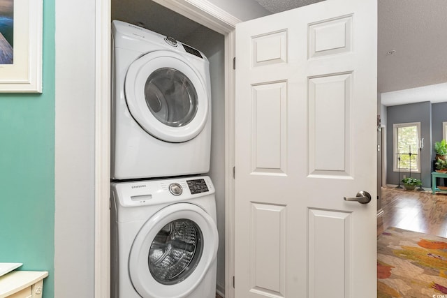 washroom with wood-type flooring and stacked washer / drying machine