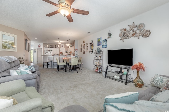 carpeted living room with a textured ceiling and ceiling fan