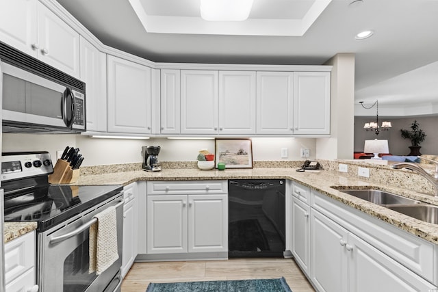 kitchen with a raised ceiling, sink, stainless steel appliances, and white cabinets