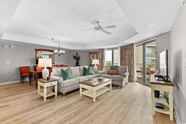 living room with ceiling fan with notable chandelier, light hardwood / wood-style flooring, and a raised ceiling