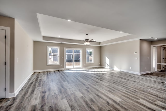 unfurnished living room featuring a raised ceiling, ceiling fan, and light hardwood / wood-style floors