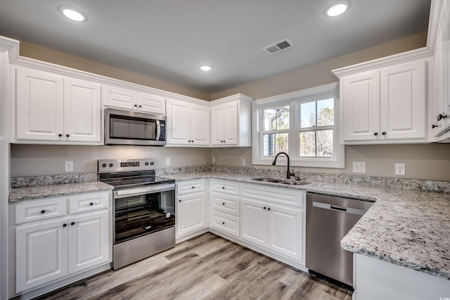 kitchen featuring light hardwood / wood-style floors, sink, stainless steel appliances, white cabinets, and light stone counters