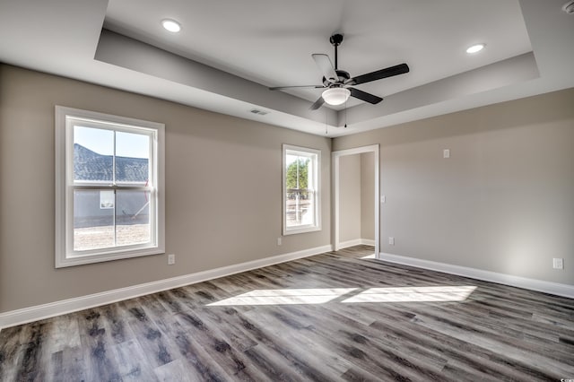 empty room featuring a raised ceiling, ceiling fan, and hardwood / wood-style flooring