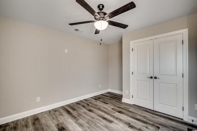 unfurnished bedroom with ceiling fan, wood-type flooring, and a closet