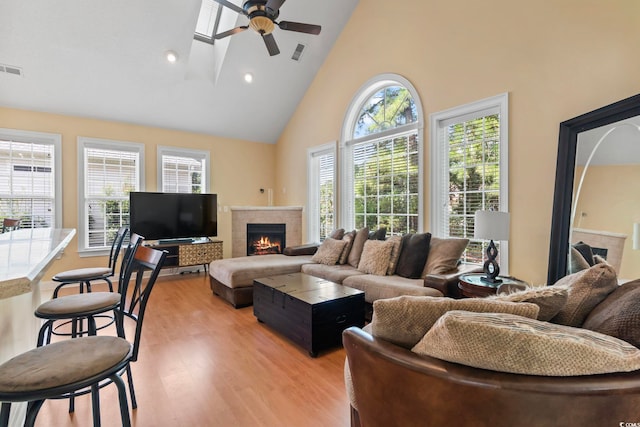 living room with high vaulted ceiling, ceiling fan, a fireplace, and light wood-type flooring