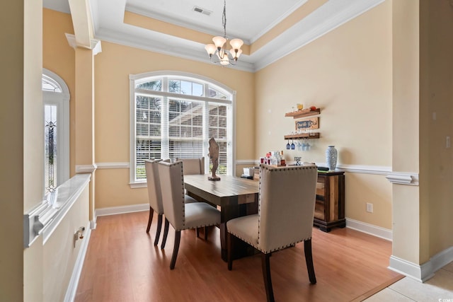 dining room with a tray ceiling, a notable chandelier, and light hardwood / wood-style floors