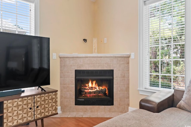 living room featuring wood-type flooring, a tiled fireplace, and a healthy amount of sunlight