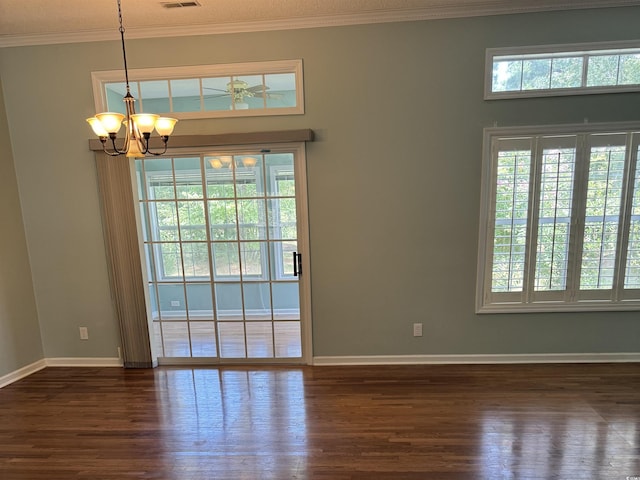 spare room featuring a chandelier, dark wood-type flooring, and crown molding