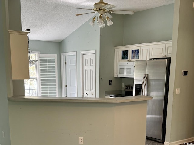 kitchen featuring ceiling fan, kitchen peninsula, a textured ceiling, stainless steel appliances, and vaulted ceiling