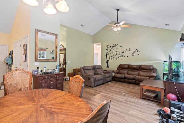 dining area with ceiling fan with notable chandelier, high vaulted ceiling, and light hardwood / wood-style flooring