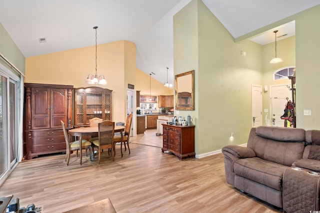 living room featuring a notable chandelier, light hardwood / wood-style flooring, and high vaulted ceiling