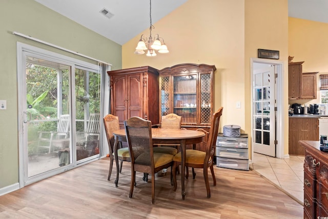 dining room featuring high vaulted ceiling, light wood-type flooring, and a chandelier