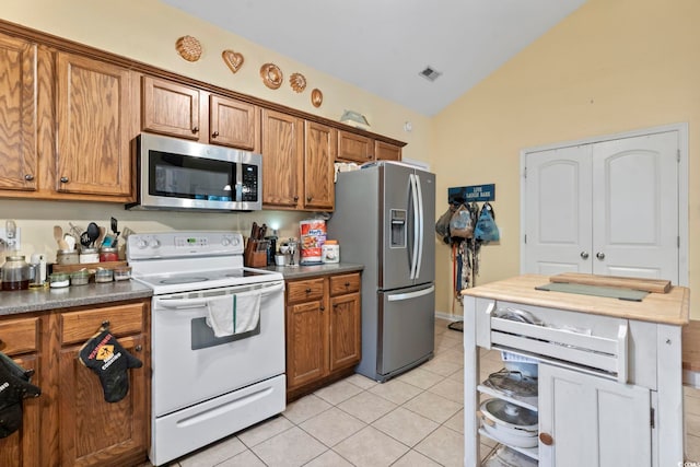 kitchen with light tile patterned floors, stainless steel appliances, and vaulted ceiling