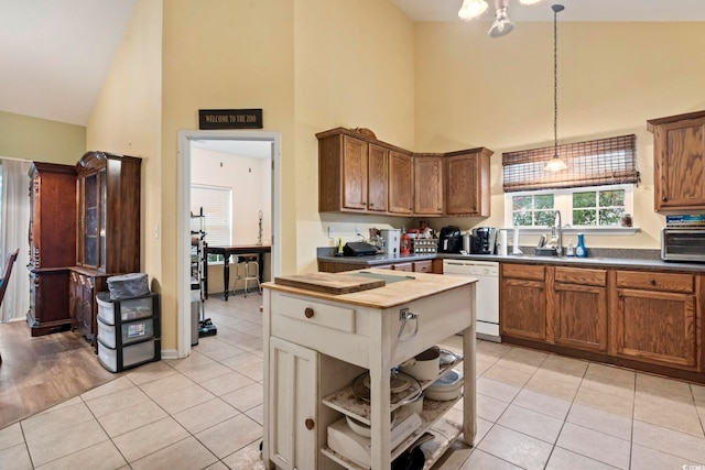 kitchen with white dishwasher, hanging light fixtures, sink, and high vaulted ceiling