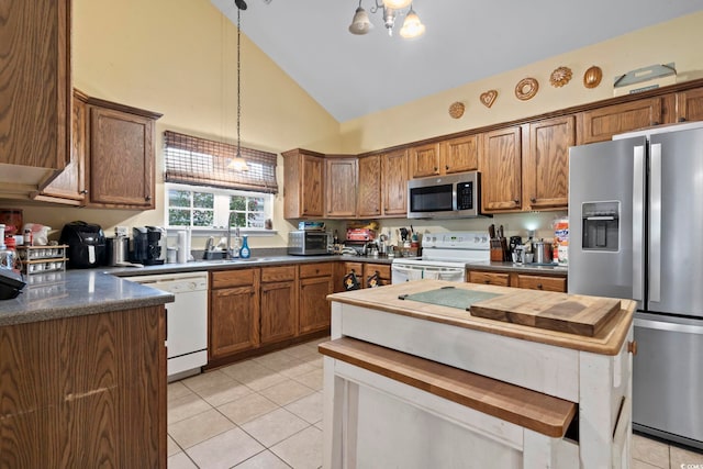 kitchen featuring pendant lighting, light tile patterned flooring, sink, high vaulted ceiling, and appliances with stainless steel finishes