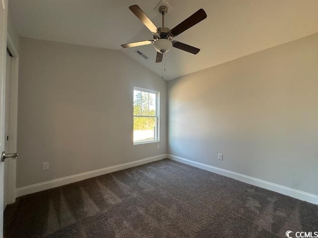 unfurnished room with vaulted ceiling, dark carpet, and baseboards