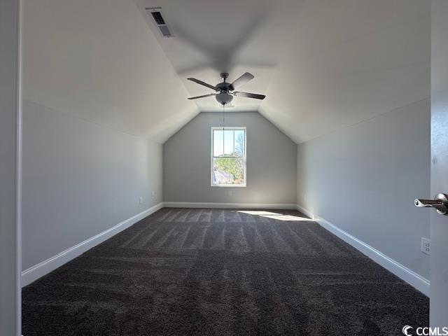 additional living space with ceiling fan, visible vents, baseboards, vaulted ceiling, and dark carpet