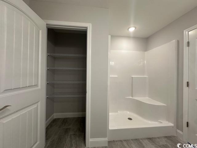 bathroom featuring a shower stall and baseboards
