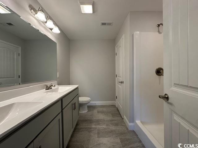 bathroom featuring toilet, double vanity, visible vents, and a sink