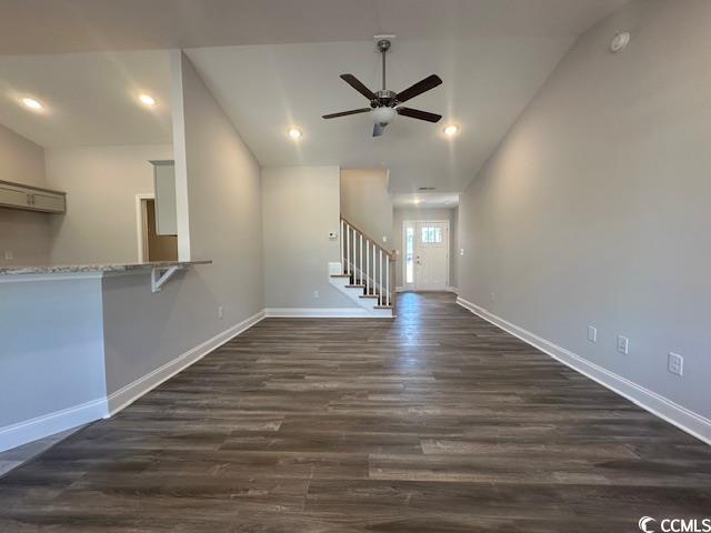 unfurnished living room with lofted ceiling, recessed lighting, dark wood-type flooring, baseboards, and stairway