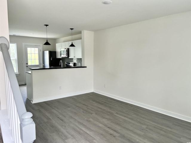 6306 Somerset Dr, Myrtle Beach, SC 29572 - kitchen with stainless steel microwave, freestanding refrigerator, backsplash, dark countertops, and dark wood-type flooring