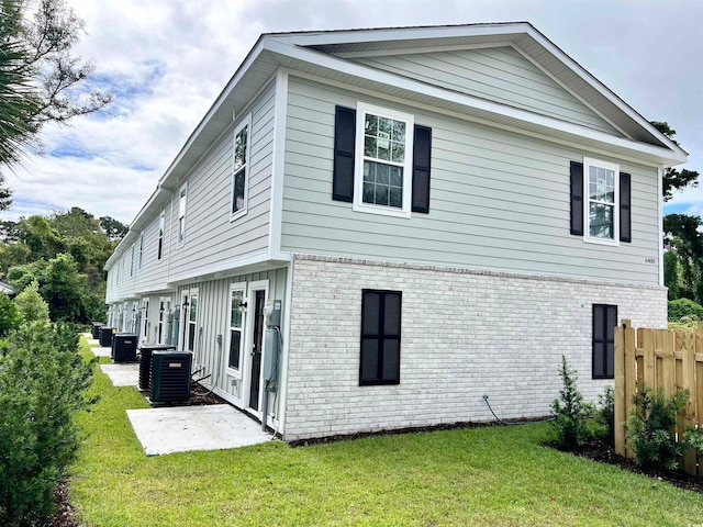 rear view of house with a lawn, a patio area, and central air condition unit