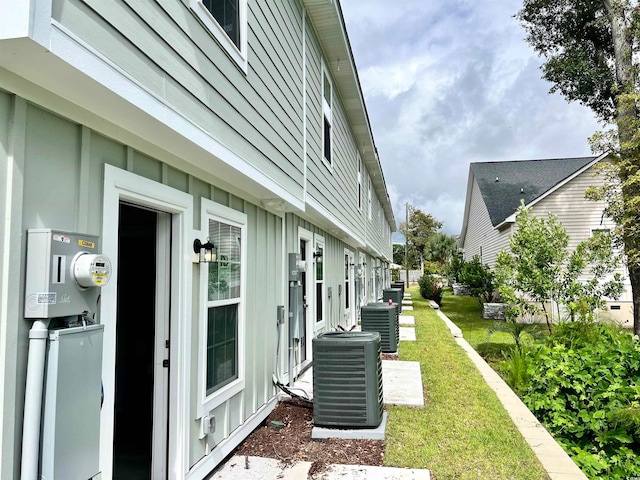 view of side of home with a lawn and cooling unit