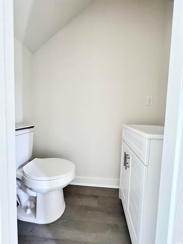 bathroom with hardwood / wood-style floors, lofted ceiling, vanity, and toilet